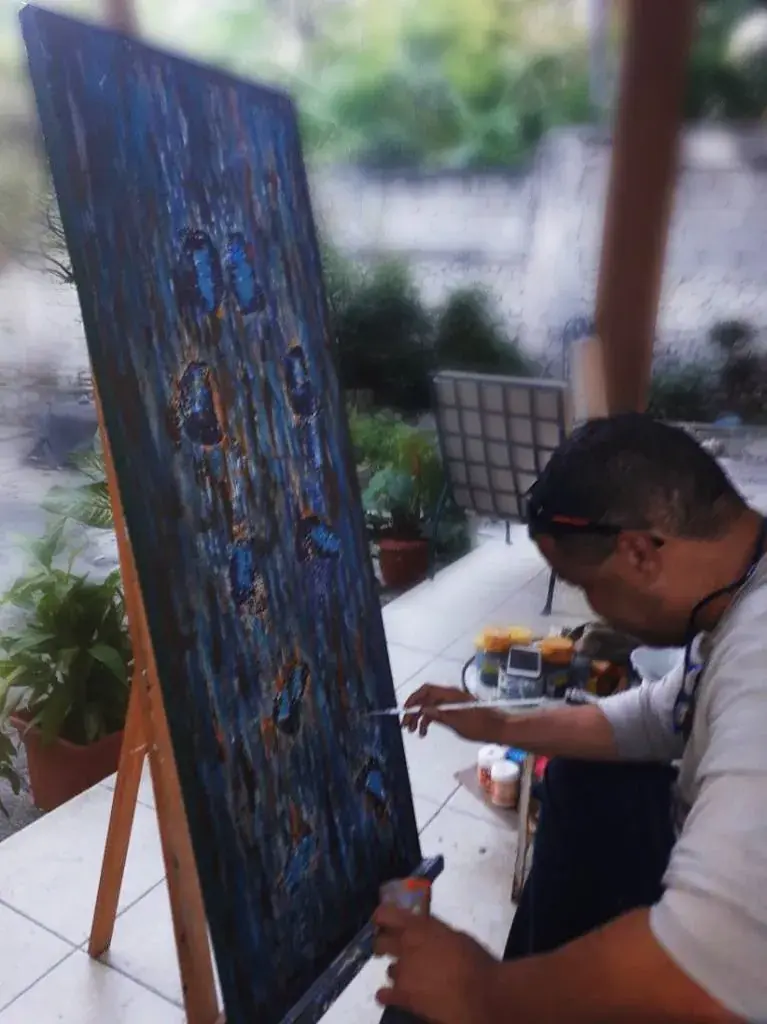 Alain Trocher painting a large dark canvas on an easel