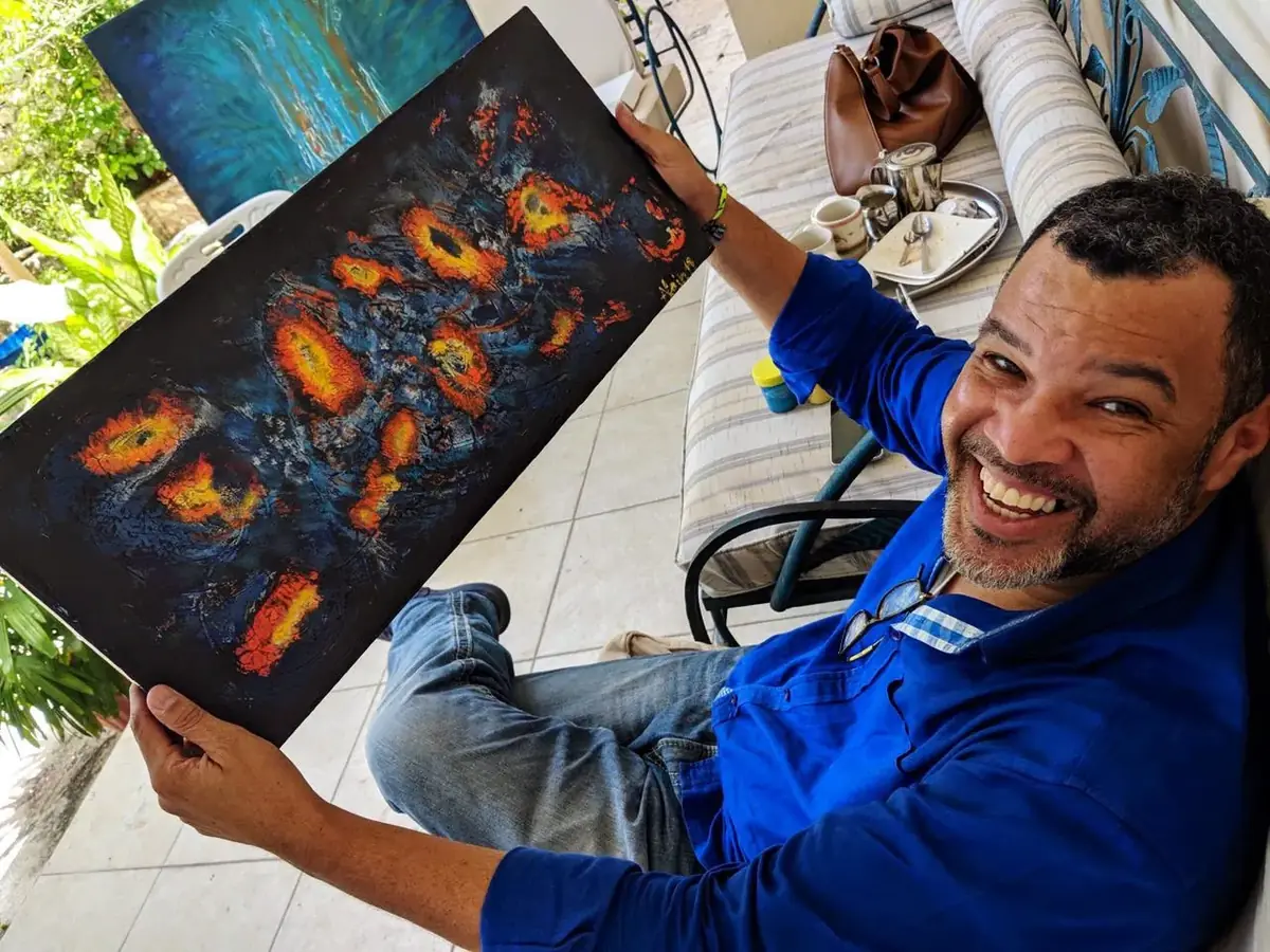 Alain Trocher smiling, holding one of his paintings